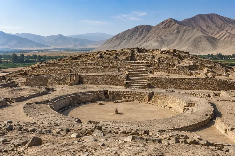 Pyramide de pierre à gradins et place circulaire en contrebas, dans une vallée désertique