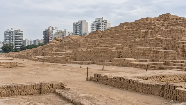 Pyramide en gradins de briques d’adobe, restaurée, avec des immeubles modernes derrière