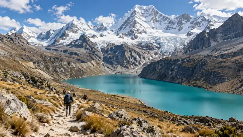 Randonneurs sur un sentier au-dessus d’une lagune turquoise, au pied de sommets enneigés et de glaciers