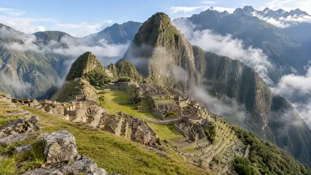 Machu Picchu vu d’en haut, terrasses et ruines sous le Huayna Picchu, nuages accrochés aux montagnes
