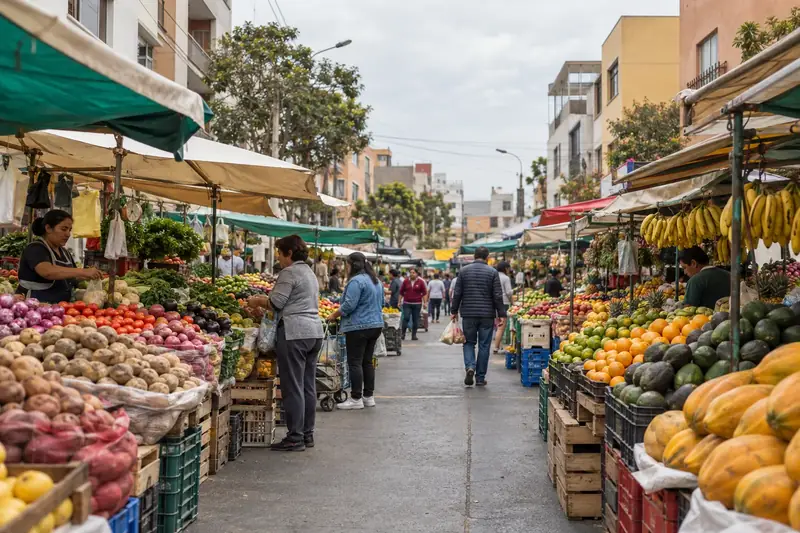 Étals de fruits et de légumes sous des bâches, dans une rue animée