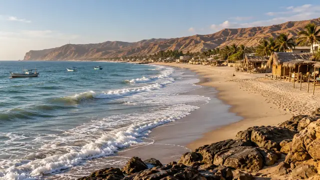 Plage de sable doré avec cabanes au toit de palmes, palmiers, barques au mouillage et collines sèches