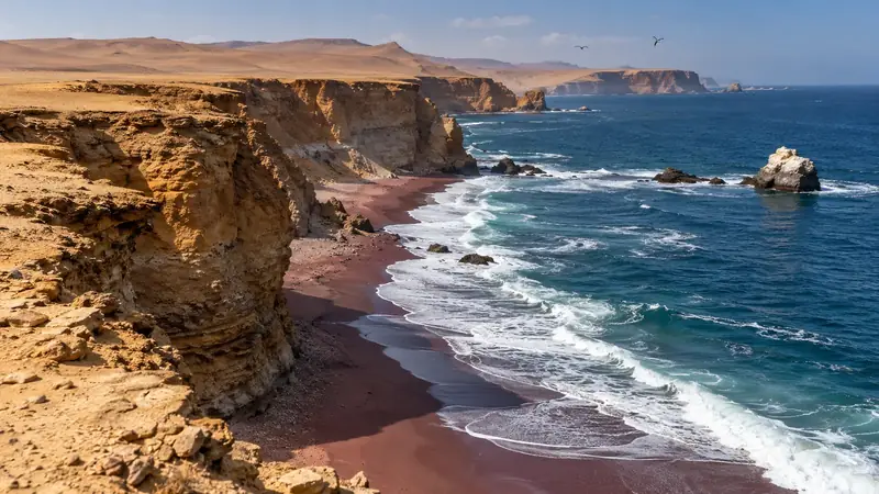Falaises du désert au-dessus d’une plage de sable rouge, vagues du Pacifique et rochers