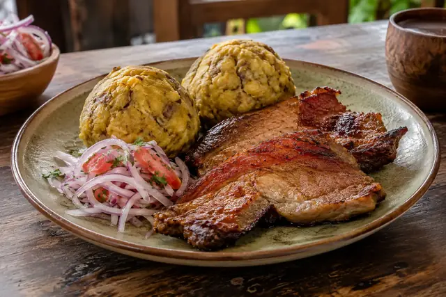 Deux boules de banane plantain grillée et écrasée, tranches de porc séché et fumé, salsa criolla