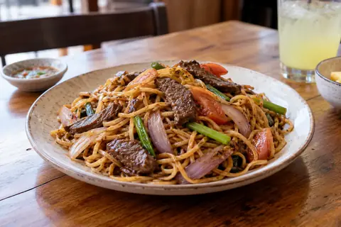 Nouilles sautées au wok avec lanières de bœuf, oignon rouge, tomate et oignon vert